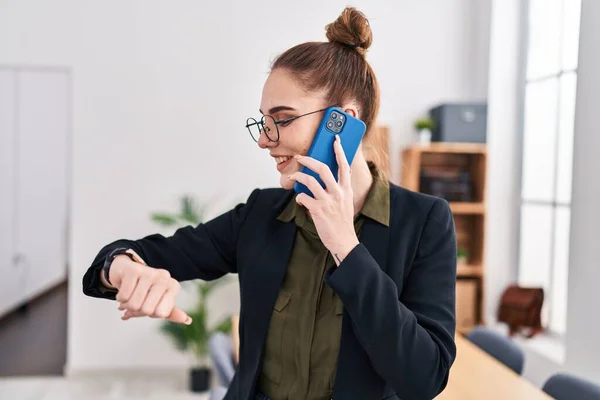 若い女性ビジネス労働者がオフィスでスマートフォンを見ながら話す — ストック写真