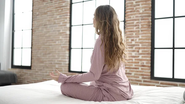 年轻美丽的惊慌失措的女人坐在床上做瑜伽练习 — 图库照片