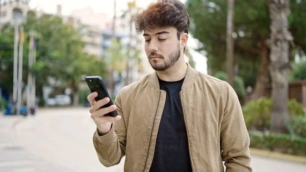 Joven Hombre Hispano Usando Smartphone Con Expresión Seria Parque —  Fotos de Stock