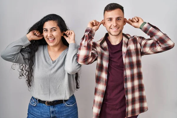 Young Hispanic Couple Standing White Background Smiling Pulling Ears Fingers — Stock Photo, Image