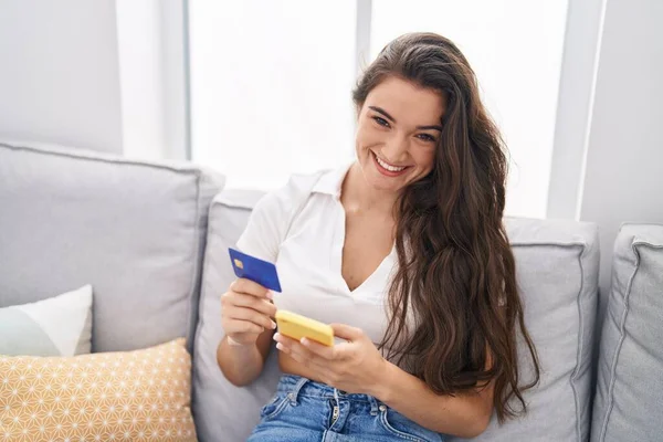 Young Hispanic Woman Using Smartphone Credit Card Sitting Sofa Home — ストック写真