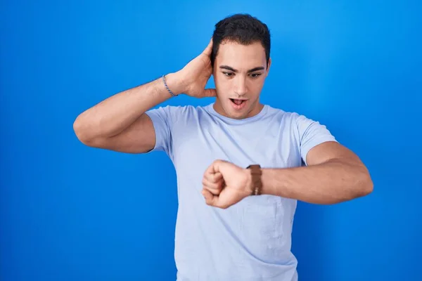 Young Hispanic Man Standing Blue Background Looking Watch Time Worried — Stock Photo, Image