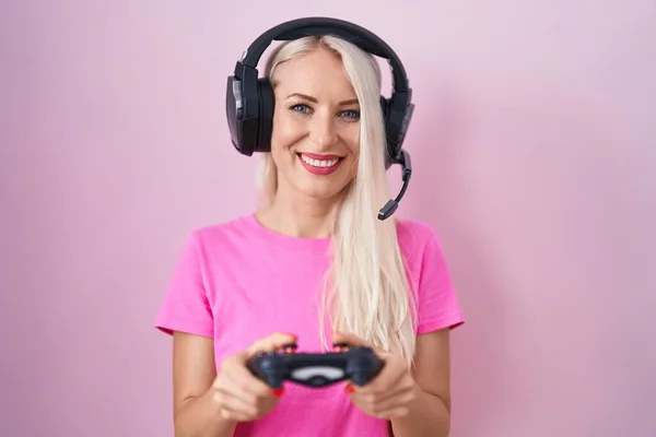 白人女性がコントローラーを持ってビデオゲームをプレイし 顔に幸せでクールな笑顔で笑っています 歯を見せて — ストック写真
