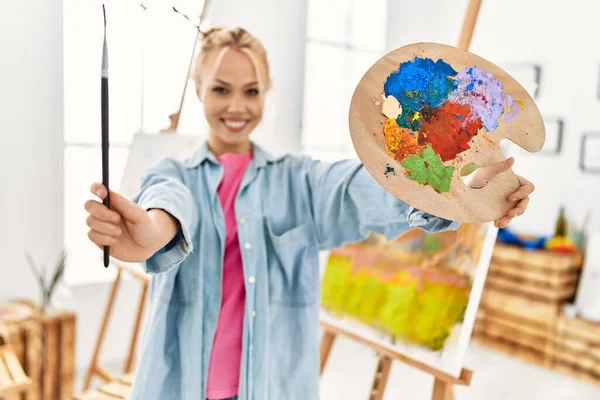 年轻的高加索女艺术家微笑着 自信地在艺术工作室拿着画笔和调色板 — 图库照片