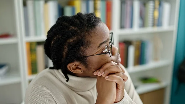 アフリカ系アメリカ人の女子学生が図書館大学で疑わしい表現で座って — ストック写真