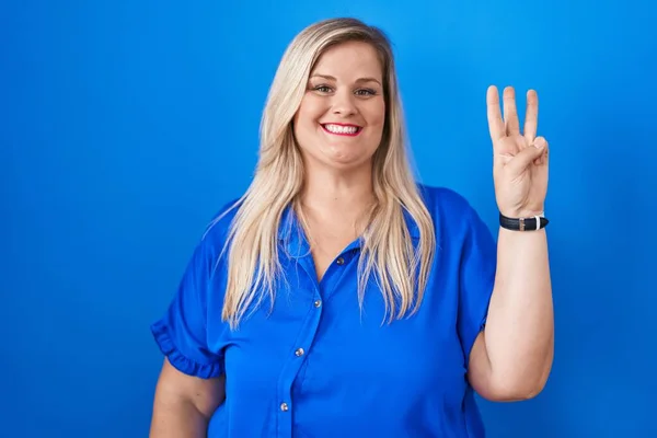 白种人加其他身材的女人站在蓝色的背景上 带着自信和快乐的笑容 用第三号手指指指着 — 图库照片