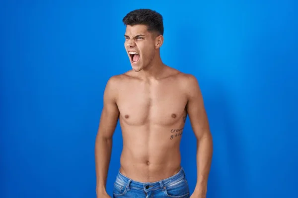 Joven Hombre Hispano Pie Sin Camisa Sobre Fondo Azul Enojado —  Fotos de Stock