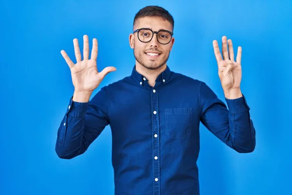 Mavi Arka Planda Gözlüklü Genç Spanyol Adam Dokuz Numaralı Parmaklarıyla — Stok fotoğraf