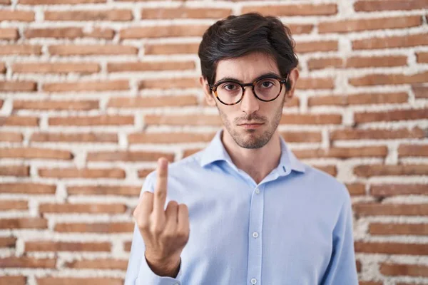 Young Hispanic Man Standing Brick Wall Background Showing Middle Finger — стоковое фото