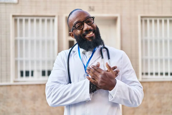 身穿医生制服的非裔美国人 戴着听诊器 双手放在胸前微笑 眼睛闭上 脸上挂着感激的手势 健康概念 — 图库照片