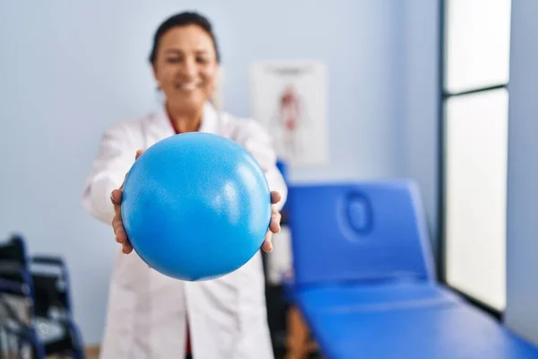 Middle Age Hispanic Woman Physiotherapist Holding Ball Rehab Clinic — Stok fotoğraf