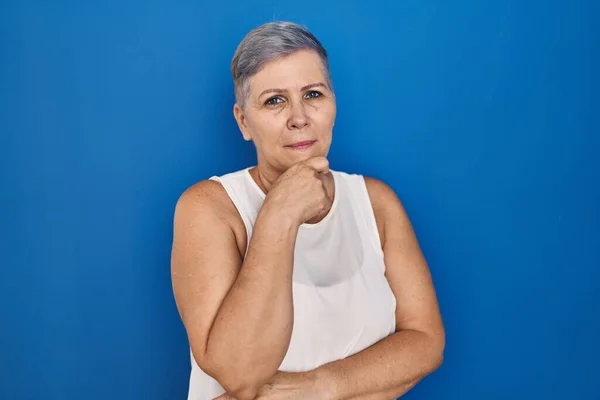 Καυκάσια Γυναίκα Μέσης Ηλικίας Στέκεται Πάνω Από Μπλε Φόντο Κοιτάζοντας — Φωτογραφία Αρχείου