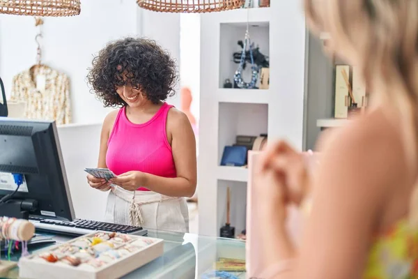 stock image Young middle eastern woman shop assistant holding dollars at clothing store