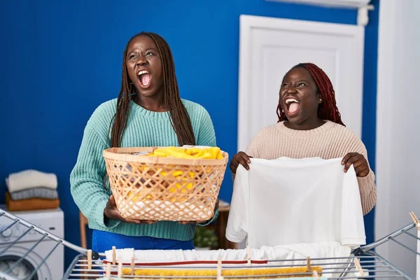 2人のアフリカ人女性が怒りと怒りの叫びで服をぶら下げている 怒りと攻撃的な考え方 — ストック写真