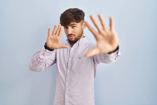 手の手のひらと指を使用してフレームを行う青の背景に立ってひげを持つアラブ人の男 カメラの視点 — ストック写真