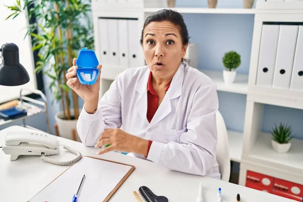 Hispanic Mature Dentist Woman Holding Invisible Aligner Orthodontic Scared Amazed — Stock Photo, Image