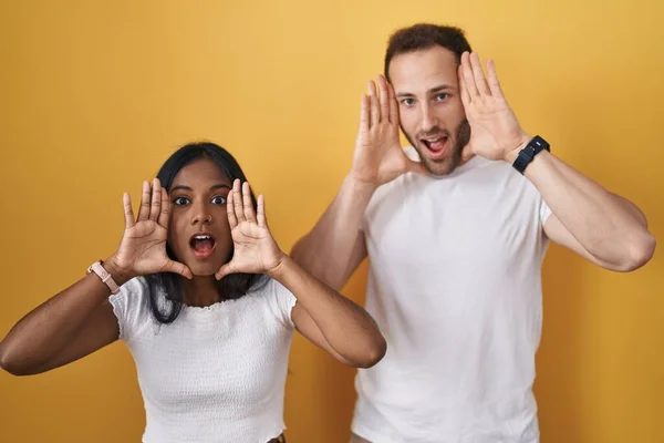 Interracial Couple Standing Yellow Background Smiling Cheerful Playing Peek Boo — Stok fotoğraf