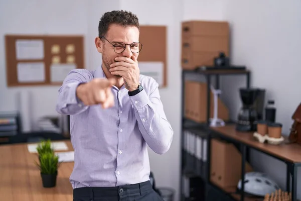 若いヒスパニック系の男がオフィスであなたを笑って 口の上に手でカメラに指を指して 恥の表情 — ストック写真
