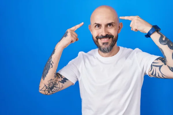 Hispánec Tetováním Stojící Nad Modrým Pozadím Úsměvem Ukazující Hlavu Oběma — Stock fotografie