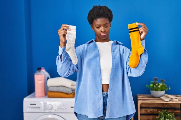 拿着干净而又脏的袜子的非洲裔美国女人很沮丧 为自己的苦恼 愤怒和害怕而忧心忡忡 悲伤的表情 — 图库照片