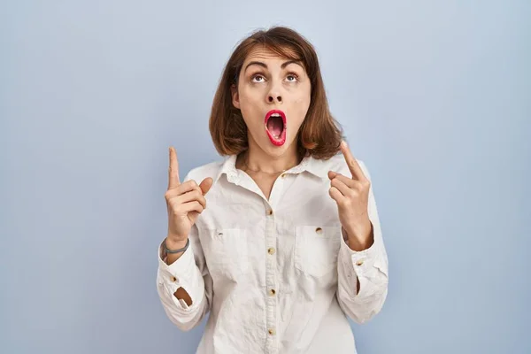 Young Beautiful Woman Standing Casual Blue Background Amazed Surprised Looking — Stock Photo, Image