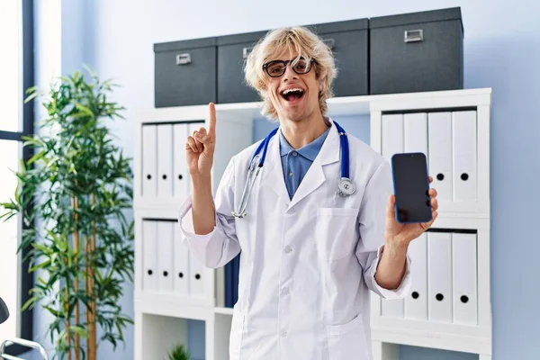 Mladý Lékař Ukazuje Obrazovku Smartphonu Úsměvem Nápadem Nebo Otázkou Ukazující — Stock fotografie