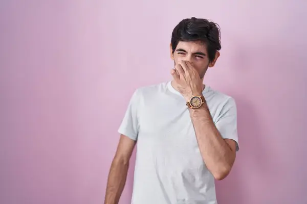 Young Hispanic Man Standing Pink Background Smelling Something Stinky Disgusting — стоковое фото