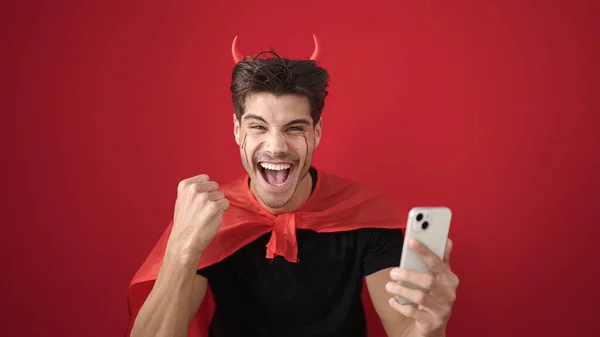 Giovane Uomo Ispanico Indossa Costume Diavolo Utilizzando Smartphone Sfondo Rosso — Foto Stock