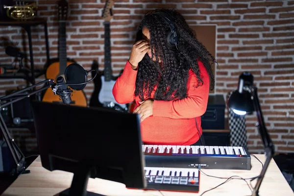 stock image Plus size hispanic woman playing piano at music studio tired rubbing nose and eyes feeling fatigue and headache. stress and frustration concept. 