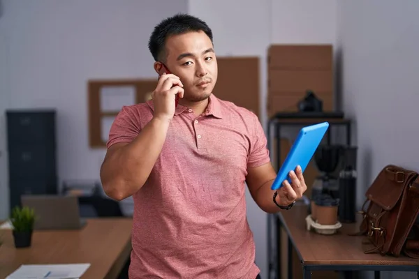 Young Chinese Man Business Worker Talking Smartphone Using Touchpad Office — Stockfoto