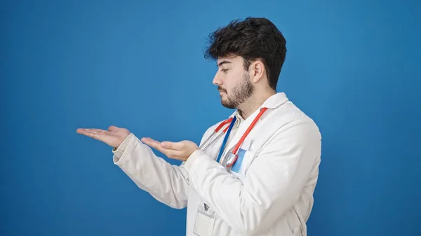 Młody Latynos Mężczyzna Lekarz Prezentuje Odizolowanym Tle Niebieski — Zdjęcie stockowe