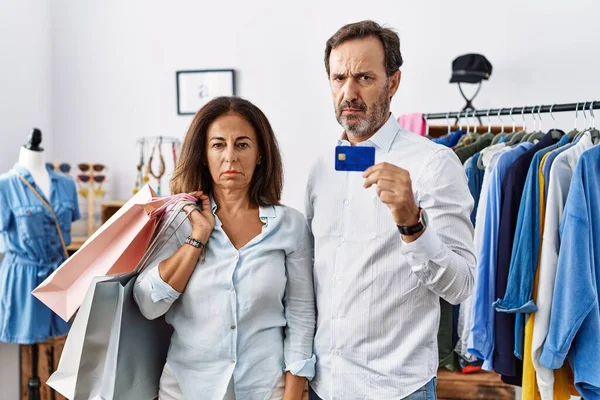 ヒスパニック系の中年のカップルのショッピングバッグやクレジットカードの懐疑的かつ神経を保持し 問題のために動揺を眉をひそめて 否定的な人 — ストック写真
