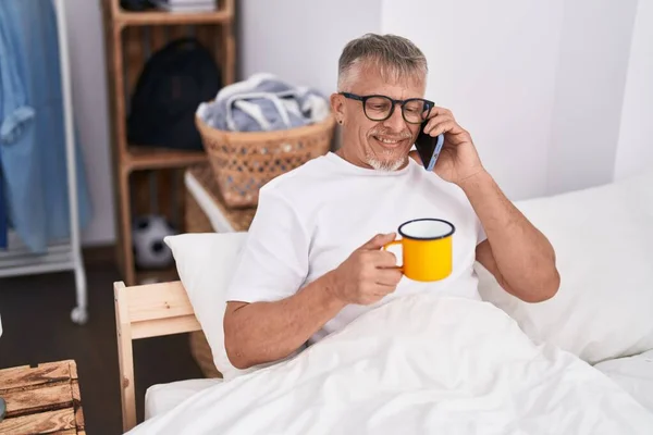 Μεσήλικας Γκριζομάλλης Που Μιλάει Στο Smartphone Πίνοντας Καφέ Στο Υπνοδωμάτιο — Φωτογραφία Αρχείου