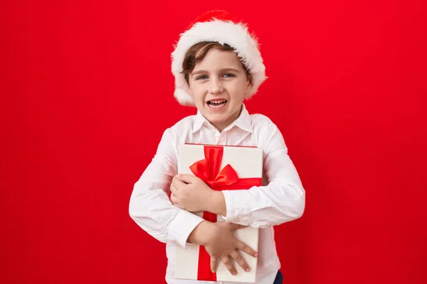 Pequeño Chico Caucásico Usando Sombrero Navidad Sosteniendo Regalos Sonriendo Riendo —  Fotos de Stock