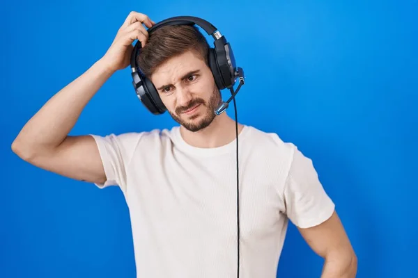 留胡子的西班牙裔男人戴着耳机听着音乐 对问题感到困惑和好奇 拿不定主意 手拿着头思考 沉思的概念 — 图库照片