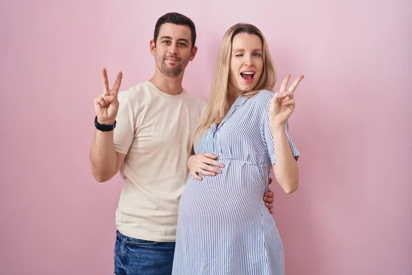 Casal Jovem Esperando Bebê Sobre Fundo Rosa Sorrindo Com Rosto — Fotografia de Stock