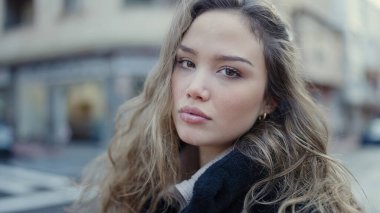 Young beautiful hispanic woman standing with relaxed expression at street