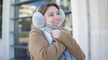 Sokakta kendine güvenen, kulaklık ve eşarp takan genç sarışın kadın.