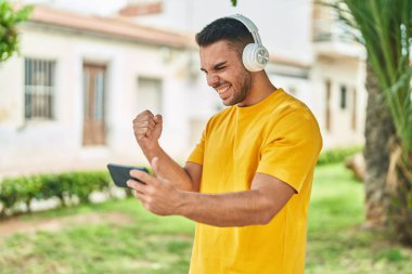 Parkta video oyunu oynayarak kendine güvenen İspanyol genç adam.