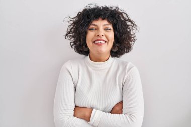 Kıvırcık saçlı İspanyol kadın izole edilmiş arka planda durup kollarını kavuşturup kameraya bakarken gülümsüyor. pozitif kişi. 