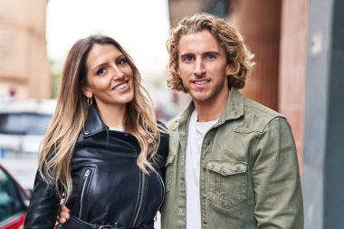 Erkek ve kadın bir arada durarak gülümsüyor.