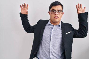 Down sendromlu genç İspanyol adam iş stili giyiniyor korku ifadesinden korkuyor ve dehşete düşüyor. El hareketlerini bırak, şok içinde bağır. panik konsepti. 