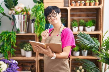 Çiçekçide çiçekçi, orta yaşlı Çinli kadın şüpheli bir ifadeyle defter okuyor.