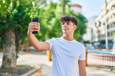 Young hispanic teenager smiling confident making selfie by the smartphone at park