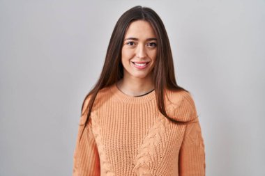 Yüzünde mutlu ve havalı bir gülümsemeyle beyaz arka planda duran esmer bir kadın. şanslı kişi. 