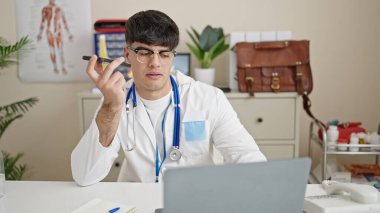 Genç İspanyol doktor bilgisayarını kullanarak klinikteki akıllı telefondan sesli mesaj gönderiyor.