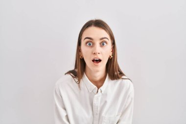 Kafkasyalı genç bir kadın izole edilmiş arka planda duruyor. Şaşırmış ve şaşırmış bir ifade, korku ve heyecanlı bir yüz ifadesi var.. 