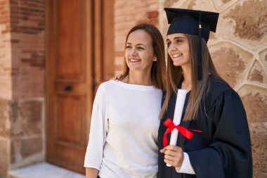 Two women mother and graduated daughter standing together at campus university