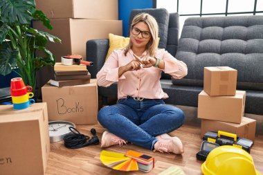 Genç İspanyol kadın yeni evine taşınıyor. Yerde oturuyor. Reddedilmiş yüz ifadesi. 