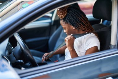 Sokakta araba kemeri takan Afrikalı Amerikalı kadın.